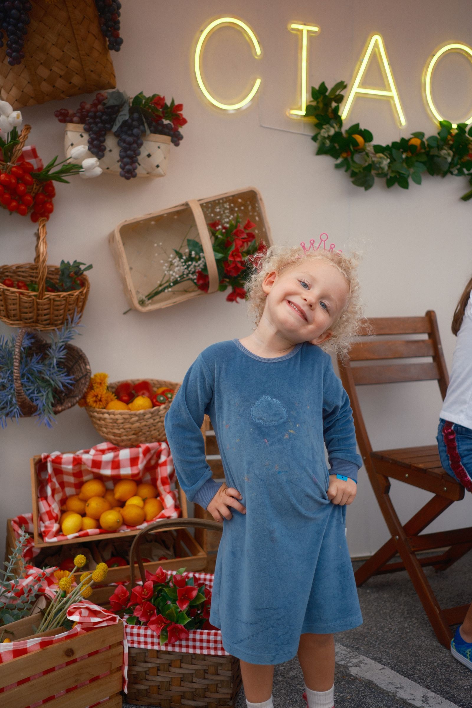 Child posing at the Ciao set among lemon crates and flowers